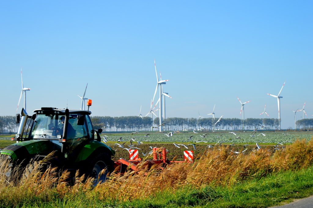 Traktor auf Feld mit Windenergieanlagen im Hintergrund